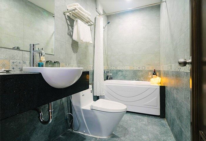 Bathroom at Spring Flower Hotel, a gay-friendly hotel. Features sink, toilet, bathtub, shower, towels, and tiled walls. Modern design.