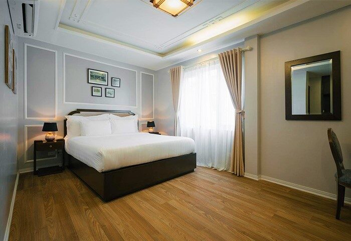 Spring Flower Hotel gay-friendly room. Bedroom with a bed, bedside tables, lamps, mirror, window with curtains, and wooden floor.