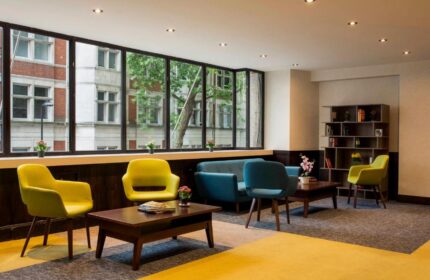 St Giles London hotel lobby. Modern seating area with yellow chairs and blue sofa. Gay-friendly, pet-friendly hotel near central London.