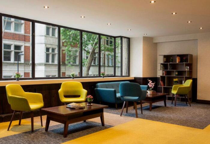 St Giles London hotel lobby. Modern seating area with yellow chairs and blue sofa. Gay-friendly, pet-friendly hotel near central London.