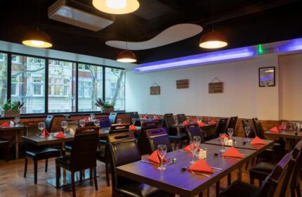 Restaurant at St Giles London Hotel. Tables set with red napkins, glasses, and cutlery. Gay-friendly, pet-friendly hotel dining.