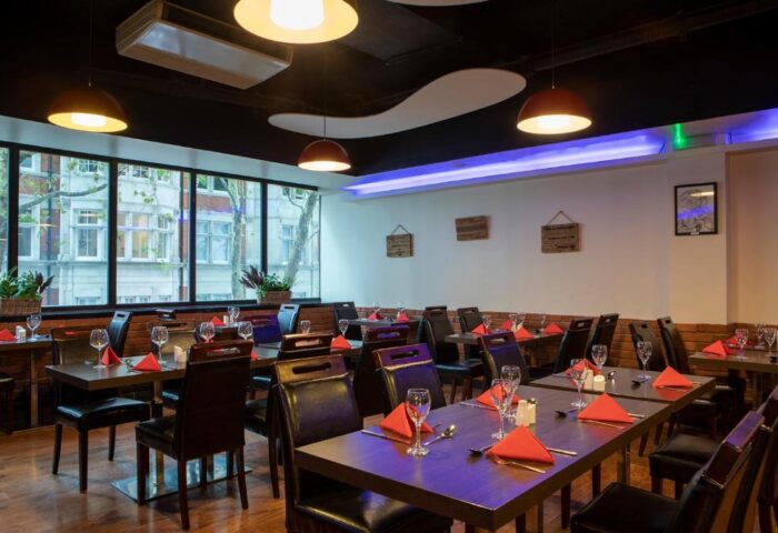 Restaurant at St Giles London Hotel. Tables set with red napkins, glasses, and cutlery. Gay-friendly, pet-friendly hotel dining.