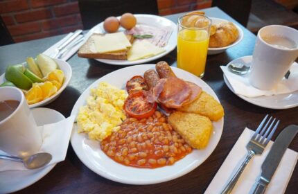 Breakfast at St Giles London Hotel. Full English breakfast with eggs, bacon, sausage, beans, hash browns, toast, juice, coffee, and fruit.