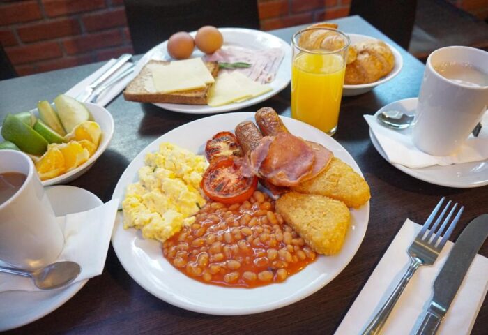Breakfast at St Giles London Hotel. Full English breakfast with eggs, bacon, sausage, beans, hash browns, toast, juice, coffee, and fruit.