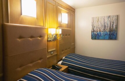 St Giles London hotel room with twin beds, striped bedding, wood paneling, and wall art. A gay-friendly, pet-friendly hotel.