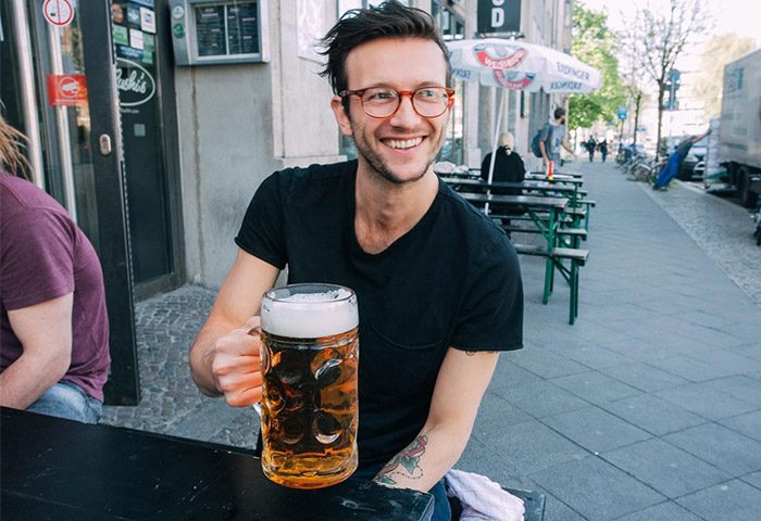 Gay-friendly St. Christopher's Hostel Berlin: Smiling man enjoying beer outside. Great spot for gay travelers in Berlin. Prost!