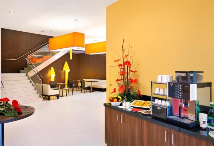 Star Inn Hotel Wien Schönbrunn lobby. Gay-friendly hotel with coffee machine, snacks, stairs, and modern design. Wien travel for gay men.