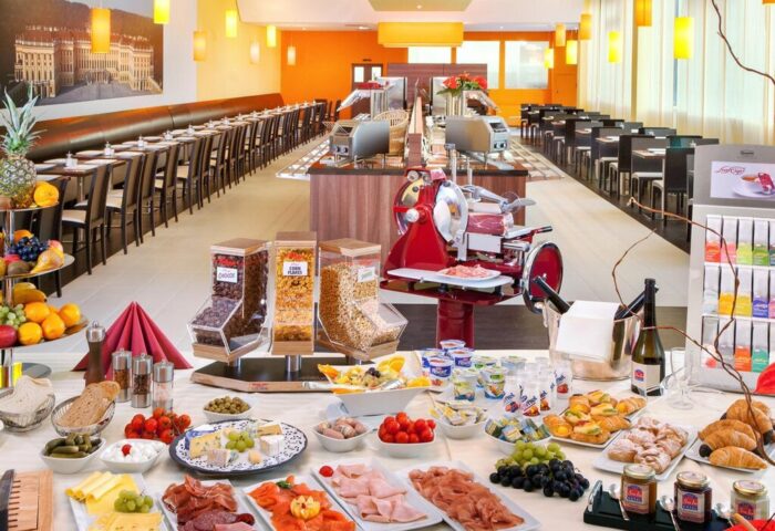 Breakfast buffet at Star Inn Hotel Wien Schönbrunn, a gay-friendly hotel. Features cereals, fruits, cheeses, meats, and pastries.