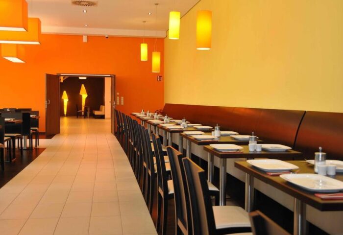 Star Inn Hotel Wien Schönbrunn's restaurant. A gay-friendly hotel with modern decor, tables set for dining, and warm lighting.