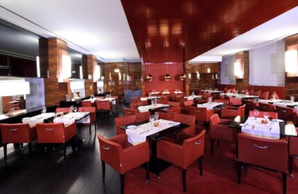 Starhotels Ritz, gay-friendly hotel restaurant. Elegant dining room with red chairs, dark tables, and wood accents. Upscale ambiance for gay travelers.