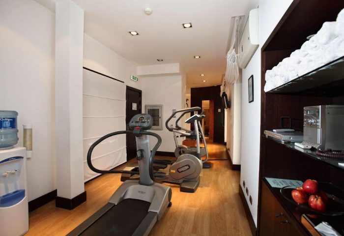 Starhotels Ritz gym. Gay-friendly hotel fitness center with treadmill, elliptical machine, water cooler, towels, and apples. Modern design.