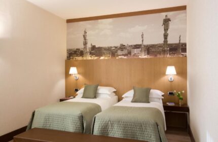 Starhotels Ritz, a gay-friendly hotel. Twin beds with Milan skyline backdrop. Comfortable stay for gay travelers in Italy.