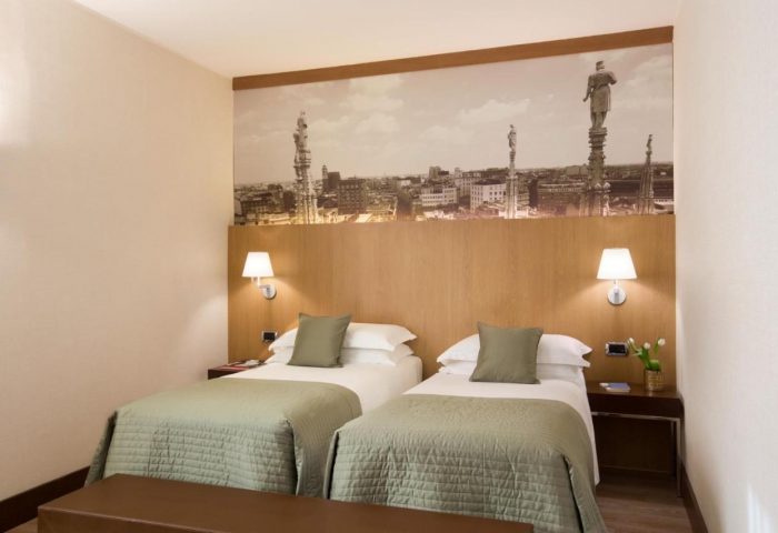 Starhotels Ritz, a gay-friendly hotel. Twin beds with Milan skyline backdrop. Comfortable stay for gay travelers in Italy.
