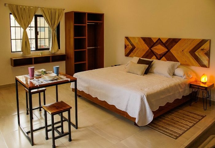 Stay Tropical gay-friendly hotel room. Modern design with wooden headboard, dining table, and closet. Relaxing space for gay travel.