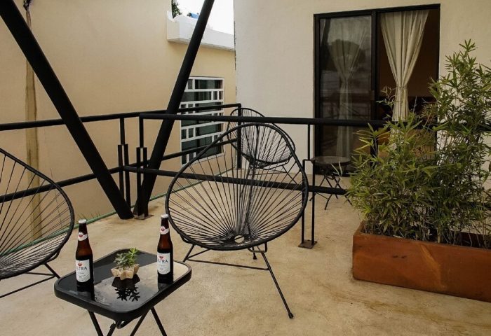 Stay Tropical gay-friendly hotel balcony with chairs, beer bottles, and plants. Relaxing outdoor space for gay men travel.