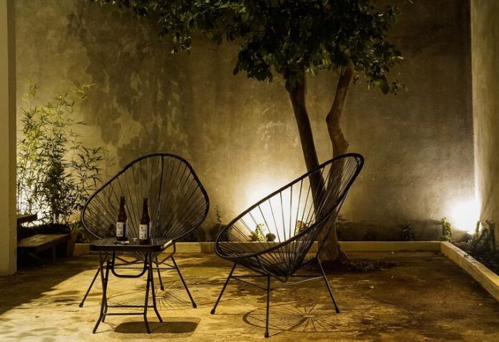 Gay-Friendly Hotel Stay Tropical: Outdoor seating area with two chairs and a table with two bottles, perfect for a relaxing tropical getaway.