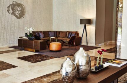 Steigenberger Hotel Köln lobby interior. Gay-friendly hotel with modern design, brown sofa, stylish vases, and warm lighting. Perfect for gay travel.