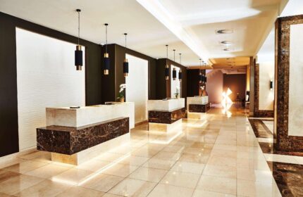 Steigenberger Hotel Köln lobby. Gay-friendly hotel reception area with marble counters, modern lighting, and polished tile floors. Upscale design.