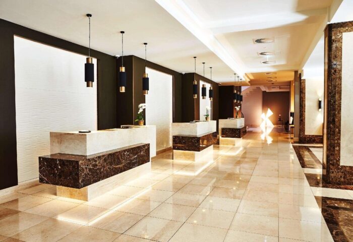 Steigenberger Hotel Köln lobby. Gay-friendly hotel reception area with marble counters, modern lighting, and polished tile floors. Upscale design.