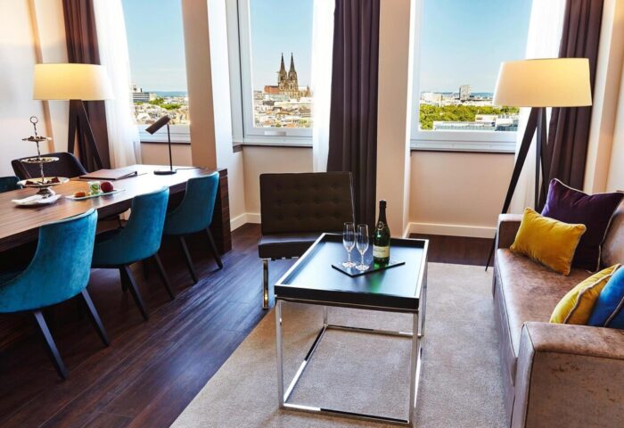 Steigenberger Hotel Köln room. Gay-friendly hotel with city view, table, and sofa. Cologne Cathedral visible. Upscale lodging for gay travelers.