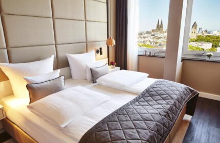 Steigenberger Hotel Köln room. Gay-friendly hotel with city view, Cologne Cathedral visible. Modern design, comfortable for gay travelers.
