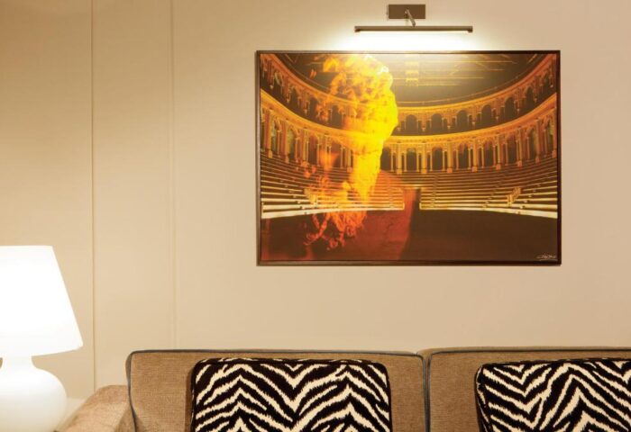 Stendhal Luxury Suites gay-friendly hotel room. Wall art of a theater with zebra print pillows on a couch. Lamp on table. Gay travel advice.