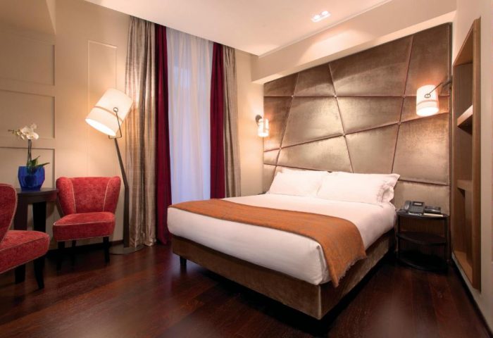 Stendhal Luxury Suites gay-friendly hotel room. Modern design with a large bed, red chairs, and stylish lighting. Ideal for gay men travelers.