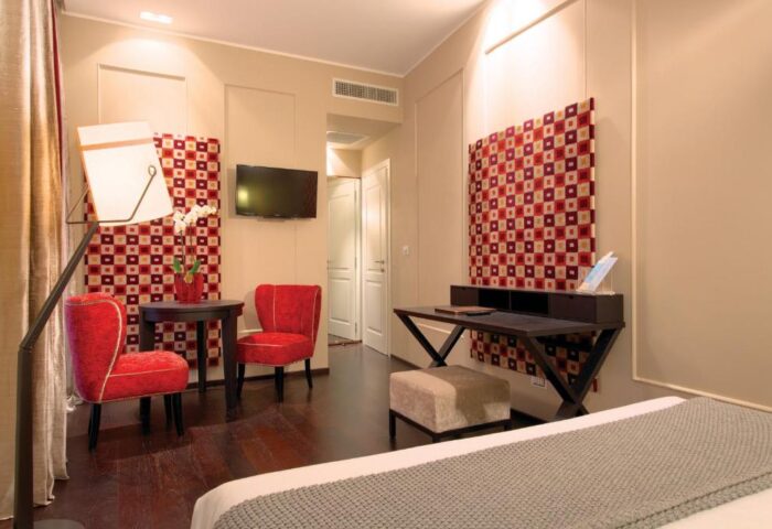 Stendhal Luxury Suites gay-friendly hotel room. Features red chairs, desk, and modern decor. Ideal for gay men travel in a stylish setting.