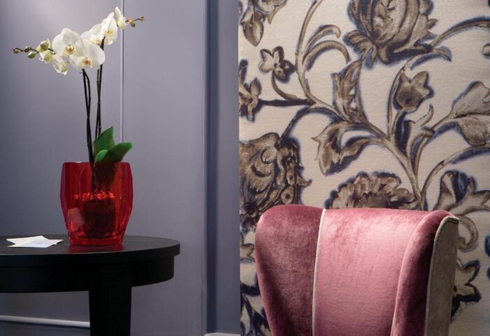 Stendhal Luxury Suites detail. Gay-friendly hotel interior with orchid, floral wallpaper, and pink velvet chair. Upscale, stylish decor.