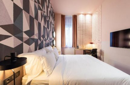 Stories Hotel Budapest room. Modern design with geometric wallpaper, desk, & TV. Gay-friendly hotel with stylish, comfortable accommodations.