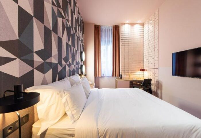 Stories Hotel Budapest room. Modern design with geometric wallpaper, desk, & TV. Gay-friendly hotel with stylish, comfortable accommodations.