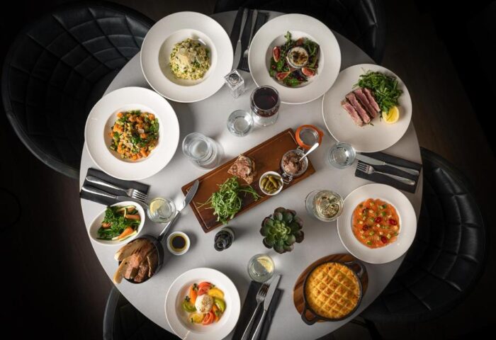 Overhead shot of a table laden with food at the gay-friendly Strand Palace Hotel. Diverse dishes, drinks, and cutlery are neatly arranged.