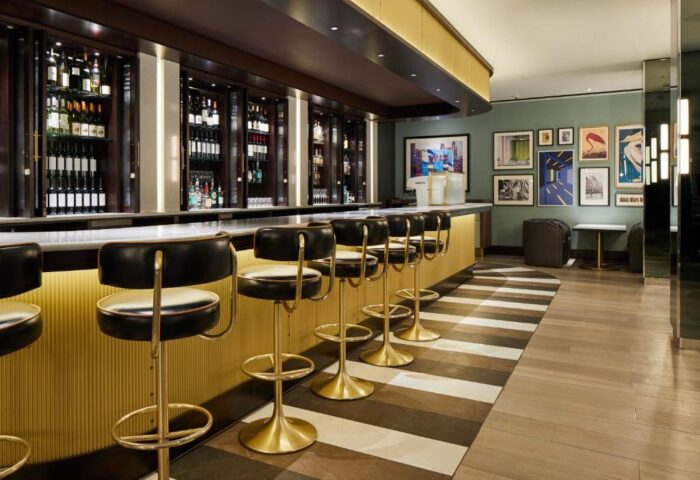 Strand Palace Hotel's stylish bar area. A gay-friendly hotel with leather bar stools, a fully stocked bar, and modern decor for a luxurious experience.