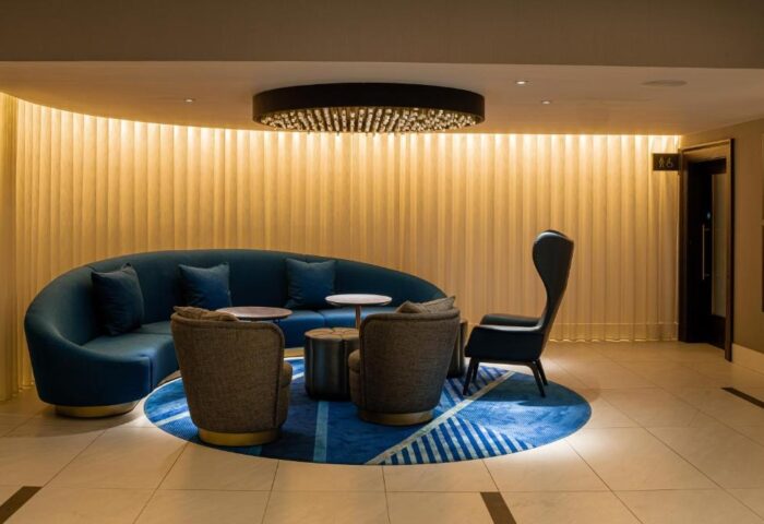 Strand Palace Hotel's stylish lounge area. Modern design with blue sofa, armchairs, and unique lighting. A gay-friendly hotel choice.
