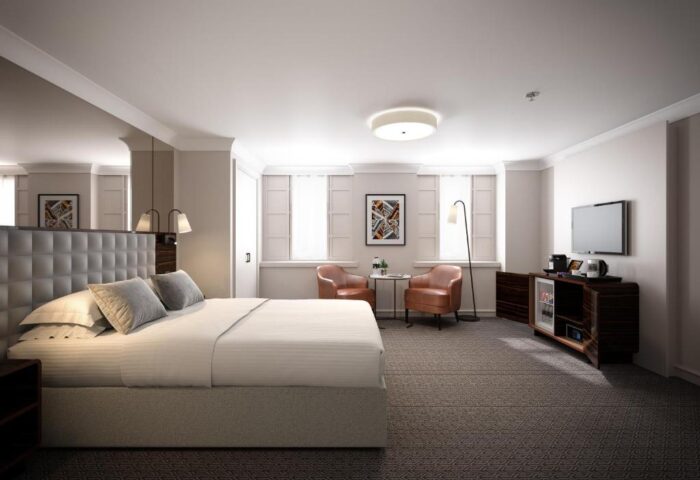 Gay-friendly Strand Palace Hotel room. Comfortable bed, chairs, TV, & minibar. Perfect for gay men's travel. Book your stay now!