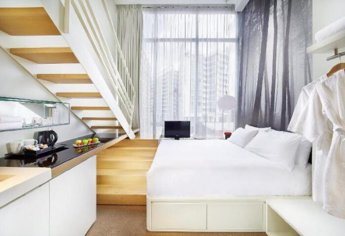 Studio M Hotel's gay-friendly room. Modern design with stairs, kitchenette, and bed. A comfortable stay for gay travelers.