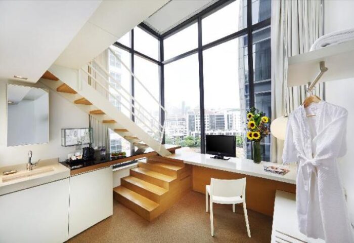 Studio M Hotel room interior. Modern design, staircase, large window with city view. Gay-friendly hotel for gay men travel.