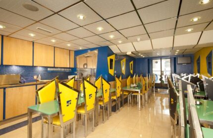 Stylotel, a gay-friendly hotel: the restaurant features a modern design with yellow chairs, blue walls, and stainless steel accents.