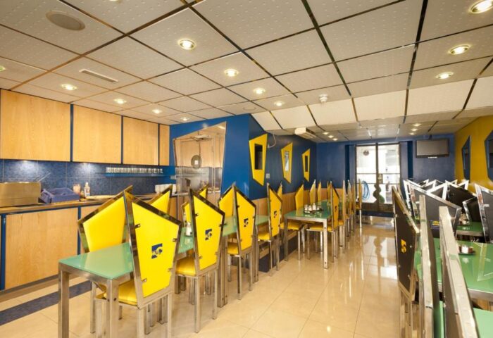 Stylotel, a gay-friendly hotel: the restaurant features a modern design with yellow chairs, blue walls, and stainless steel accents.