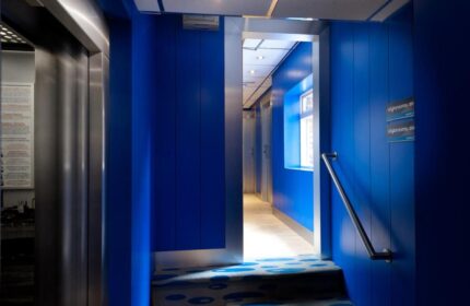 Stylotel, a gay-friendly hotel: Blue hallway with elevator and stairs. Interior design of Stylotel rooms. Modern and stylish hotel for gay travelers.