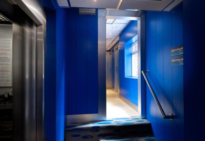 Stylotel, a gay-friendly hotel: Blue hallway with elevator and stairs. Interior design of Stylotel rooms. Modern and stylish hotel for gay travelers.