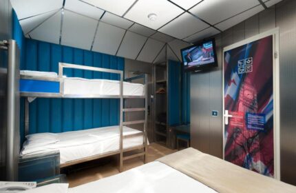 Stylotel, a gay-friendly hotel. Bunk beds, TV, and door with a Big Ben design. Modern interior. Ideal for gay men travel in style.