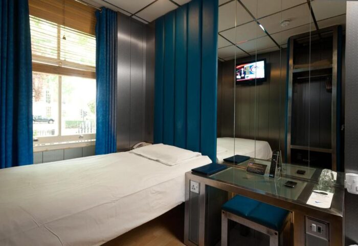 Stylotel, a gay-friendly hotel: Modern room with a single bed, blue accents, and a mirrored wall. A stylish and comfortable space for gay travelers.