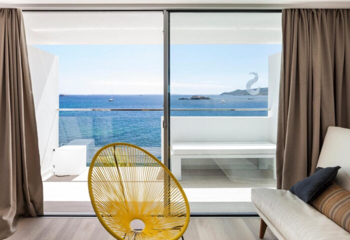 Sud Ibiza Suites gay-friendly hotel room view. Balcony with ocean view, yellow chair. Ideal gay travel destination for gay men.
