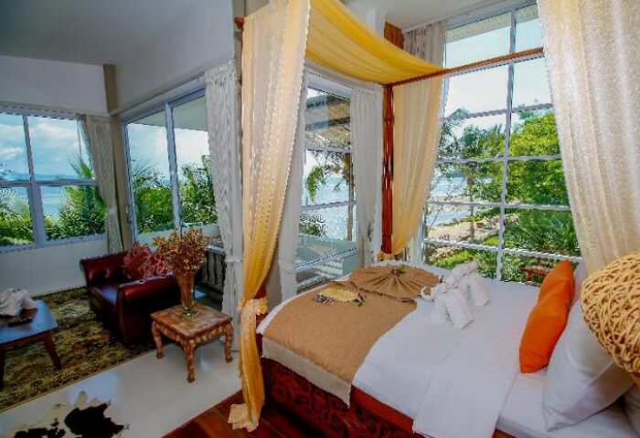 Gay-friendly Summer Luxury Beach Resort & Spa room. Canopy bed, beach view. Upscale travel for gay men. Relaxing vacation.
