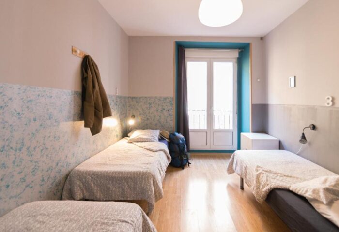 Sungate One gay-friendly hotel room with three beds, backpack, jacket, and balcony. A great choice for gay men travelers.