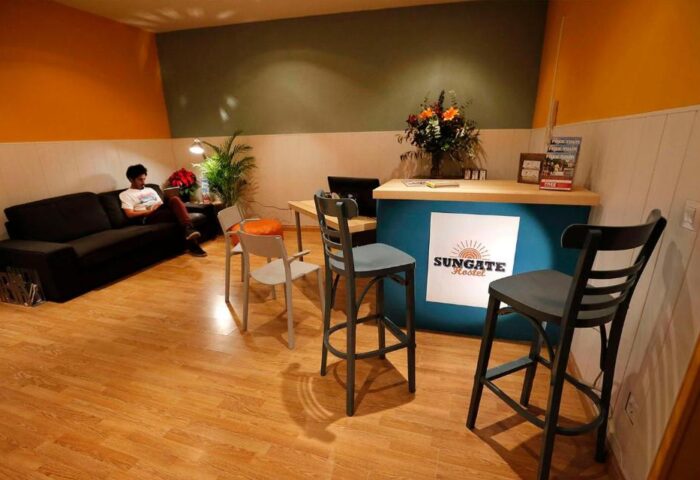 Sungate One, a gay-friendly hotel: Lobby area with reception desk, seating, and a guest relaxing on a sofa. A welcoming space for travelers.