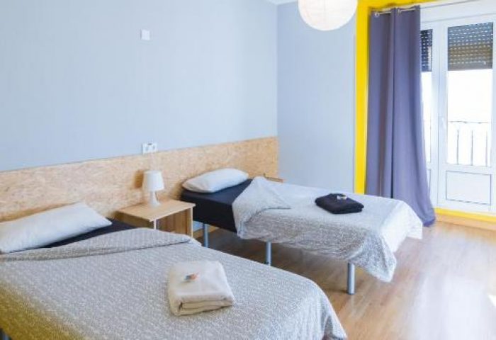 Sungate One gay-friendly hotel room with two single beds, light blue walls, and yellow window frame. Comfortable stay for gay travelers.