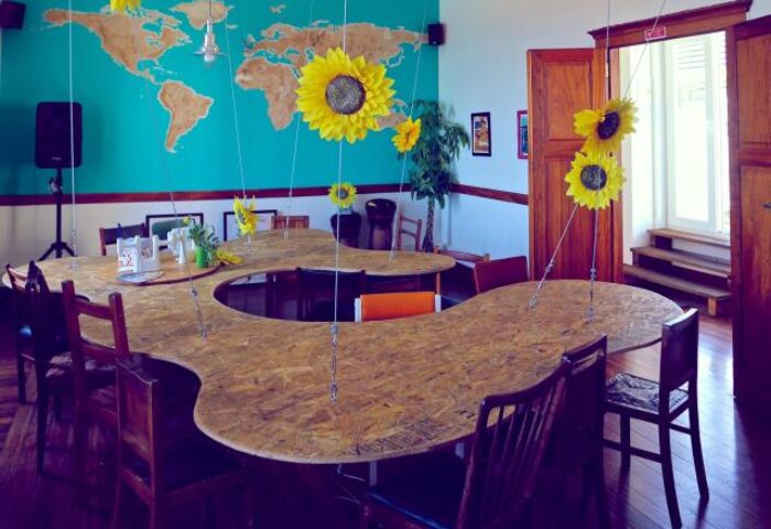 Sunset Destination Hostel's gay-friendly space: A unique table, sunflower decor, and a world map create a welcoming atmosphere.