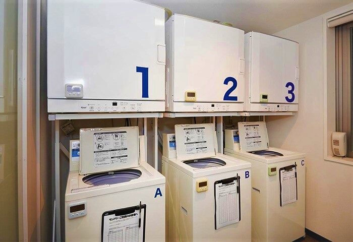 Laundry room at Super Hotel Shinjuku Kabukicho, a gay-friendly hotel in Tokyo. Washers and dryers are numbered for easy use.